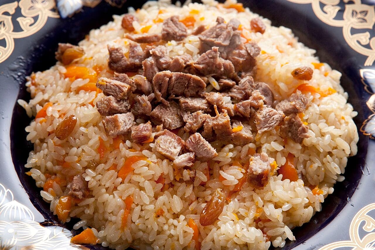 A large platter of kabuli pulao rice topped with golden carrot strips and dark raisins