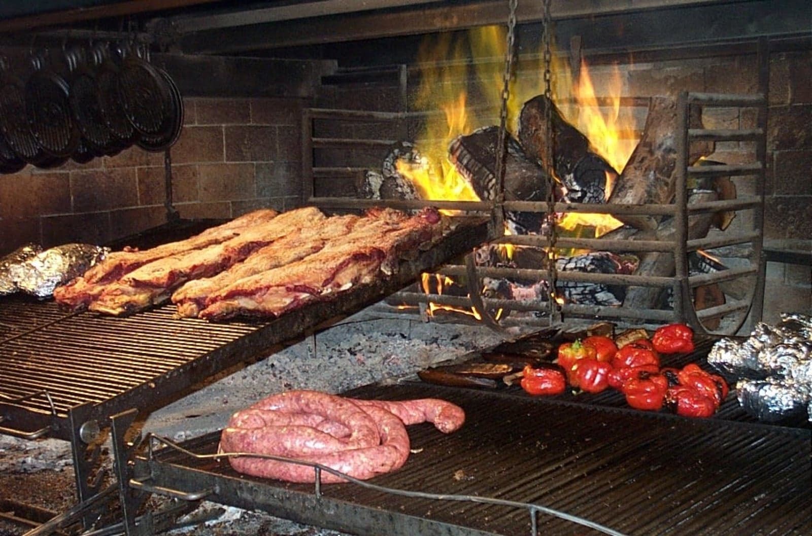 Ribs and sausages cooking over an open wood fire at an Argentine asado