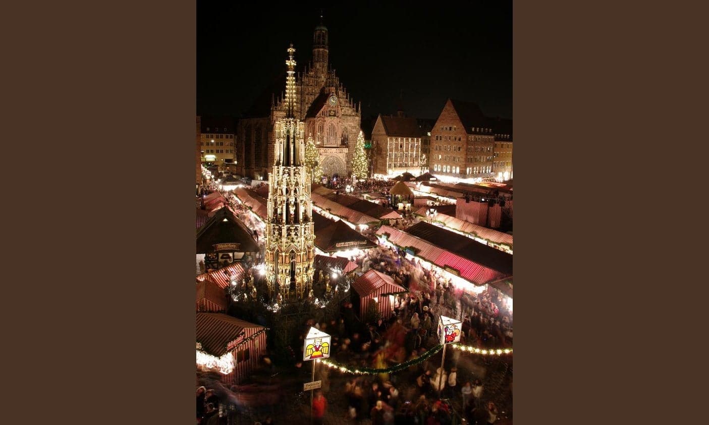 A glowing Christmas market at night in Vienna with wooden stalls, warm lights and a church behind