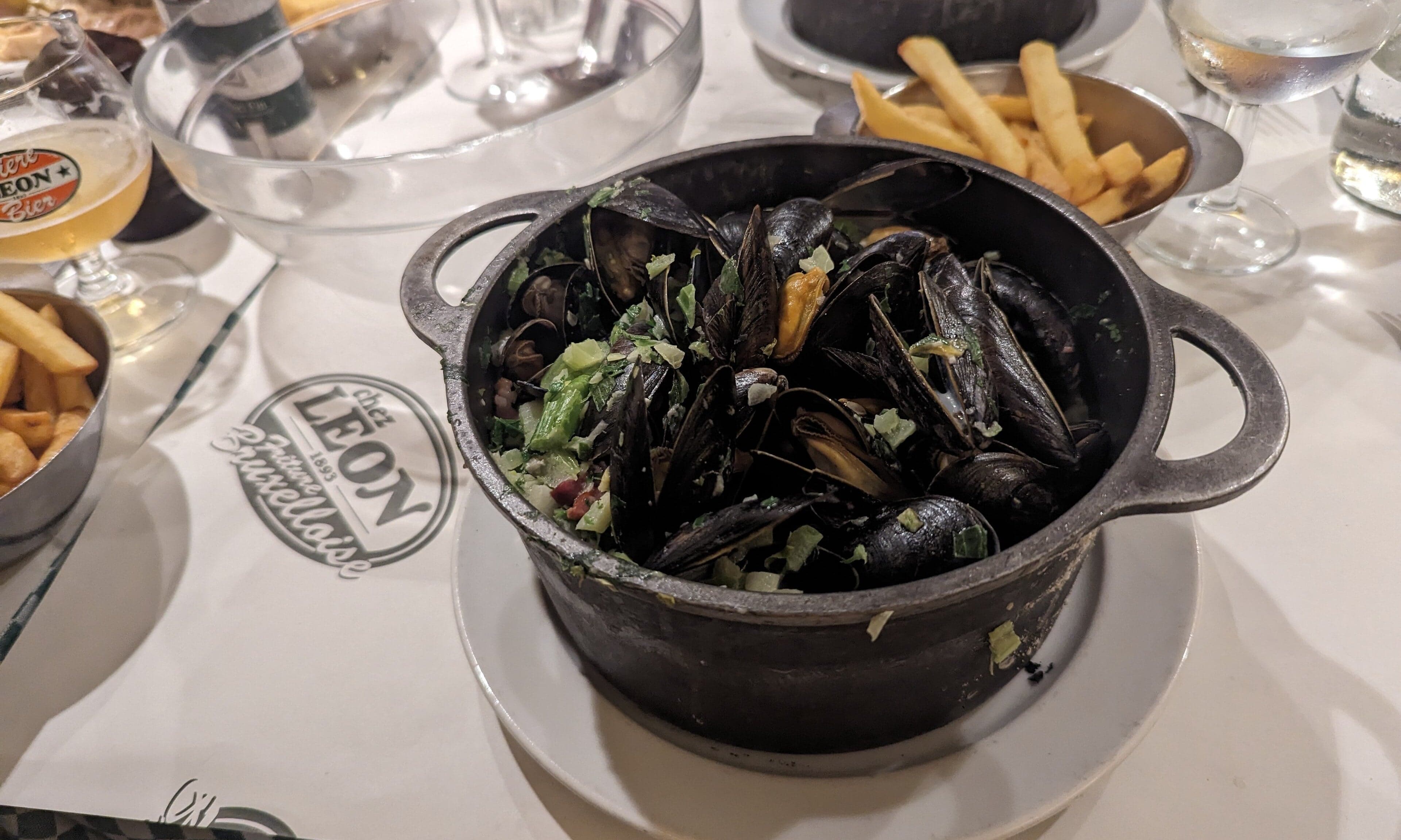 A paper cone of golden Belgian frites with a small pot of mayonnaise