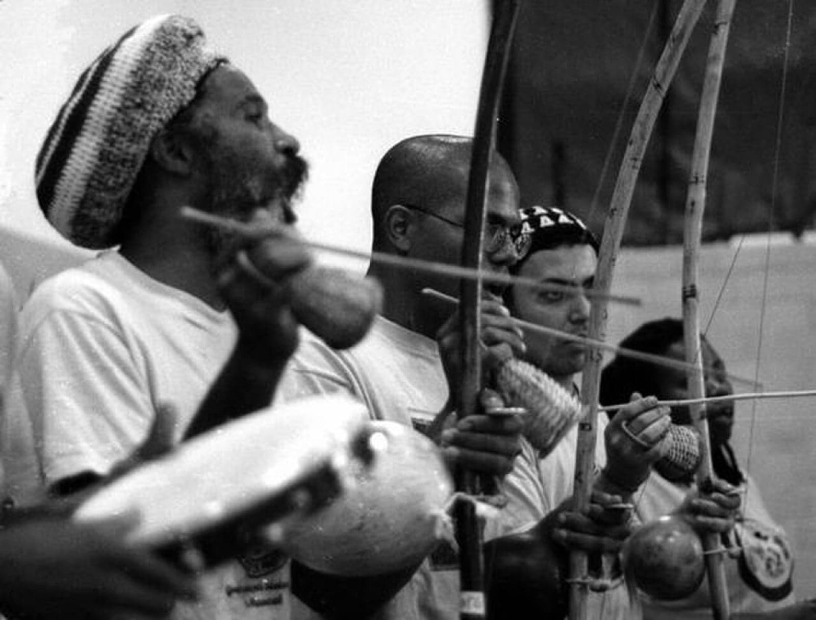 Musicians playing berimbaus and a pandeiro during a capoeira roda