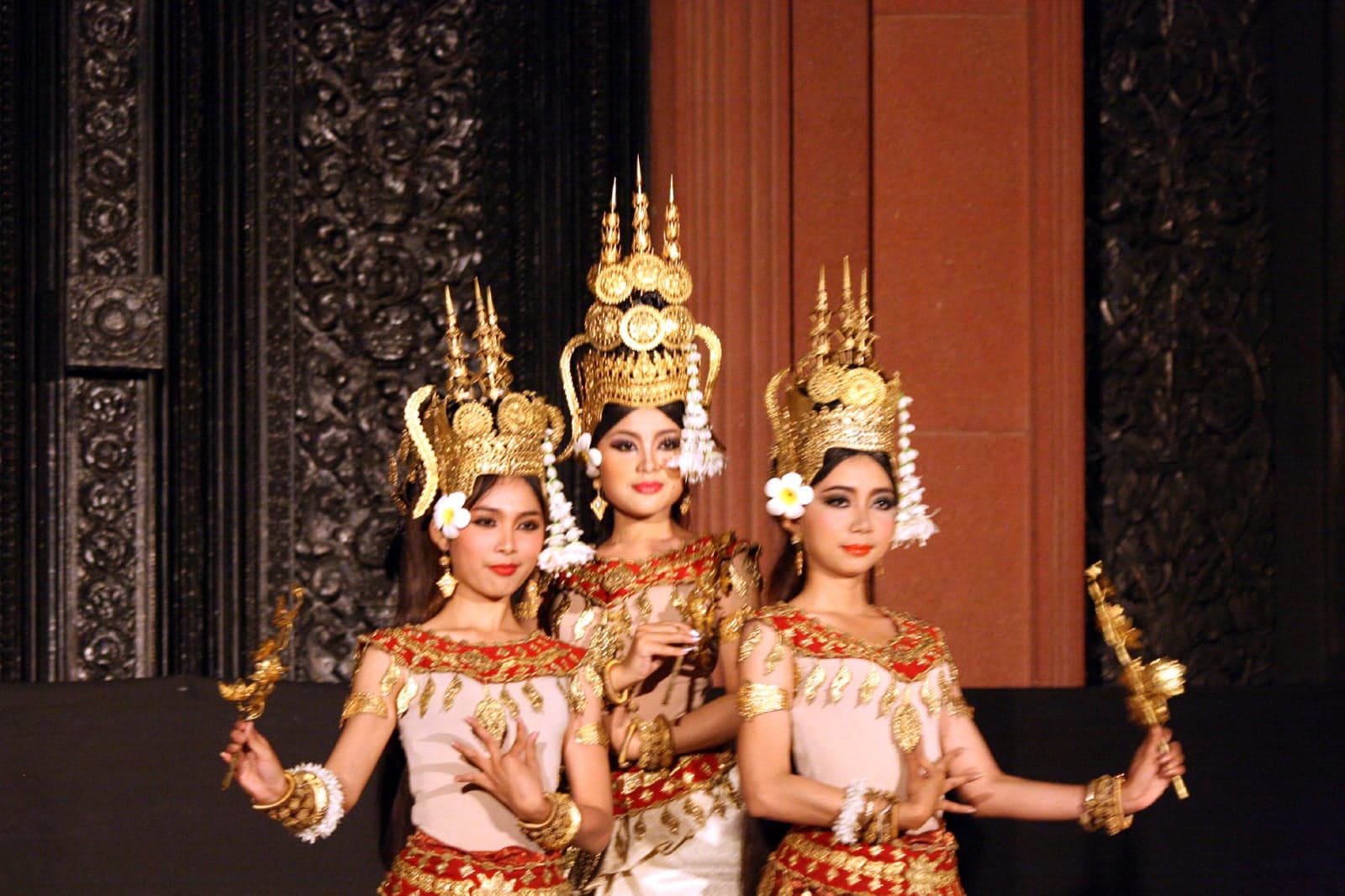 An apsara dancer in golden costume and tall crown performing with curved fingers