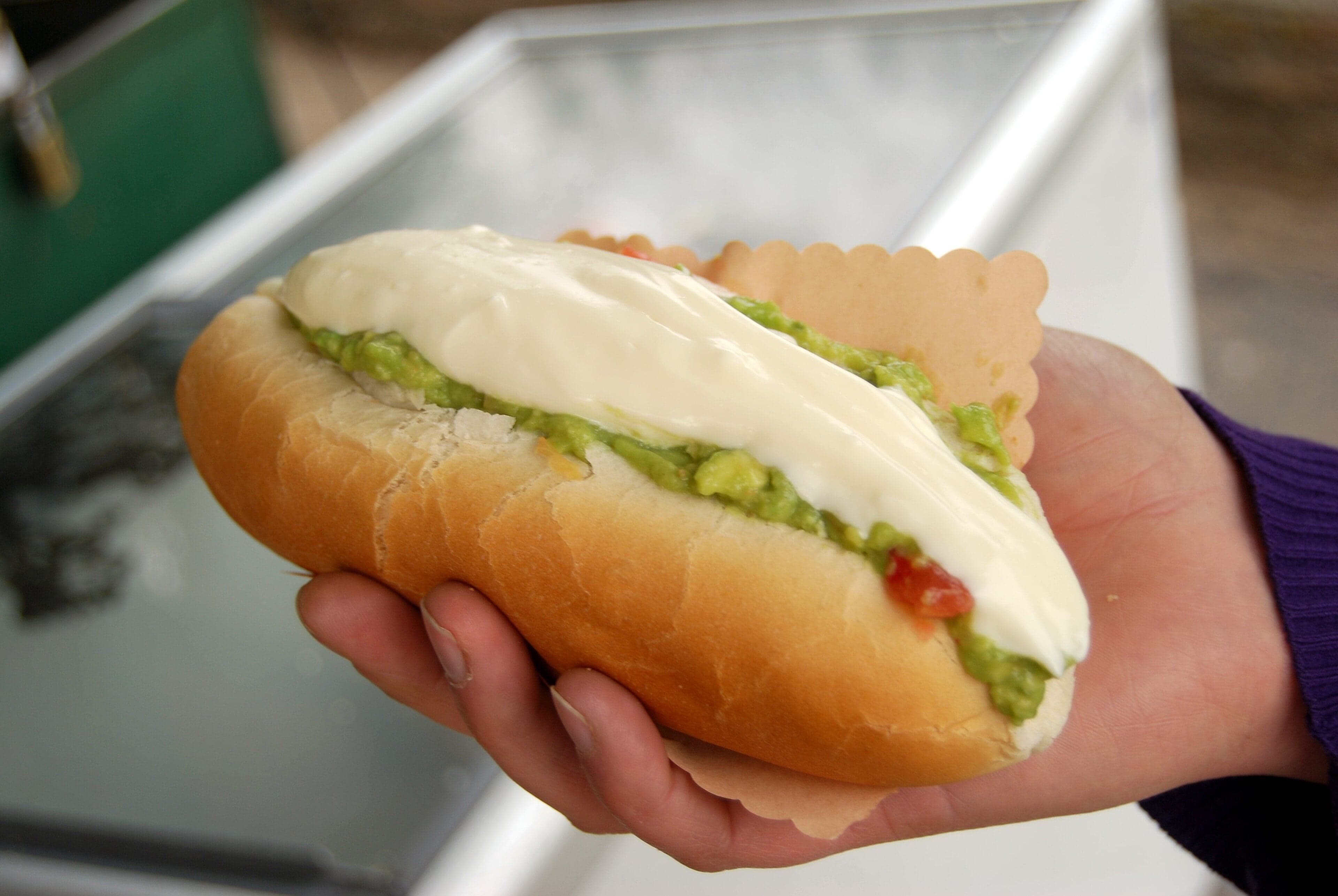 A Chilean completo hot dog piled high with avocado, tomato and mayonnaise in a soft bread roll