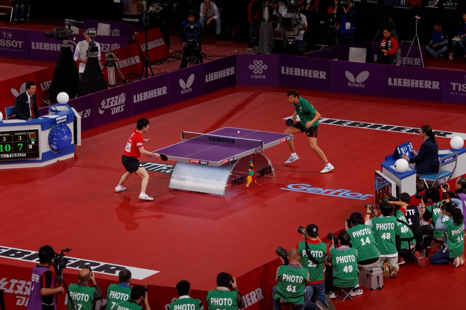 Two table tennis players in mid-rally at an international match