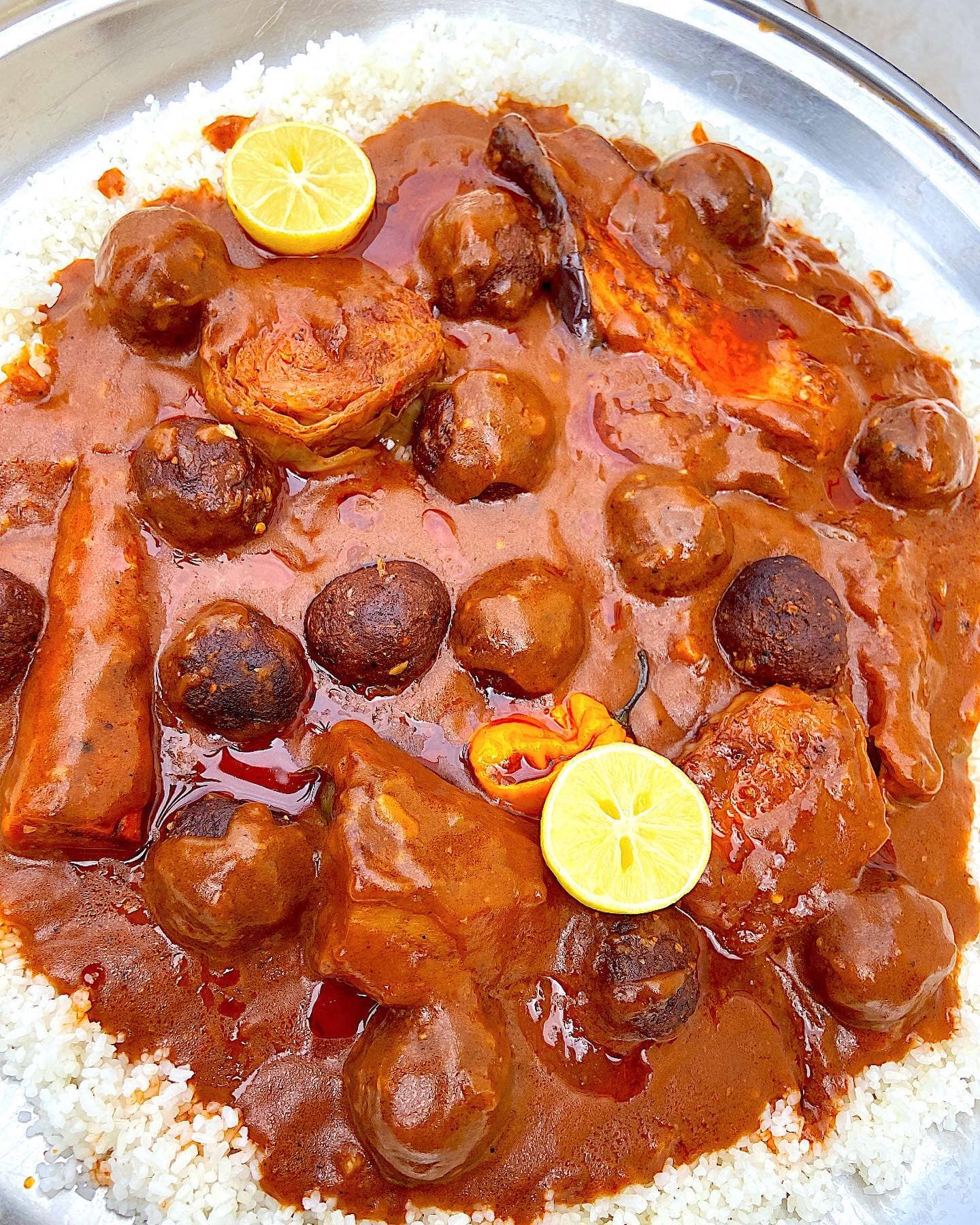 A bowl of deep orange domoda groundnut stew served with white rice