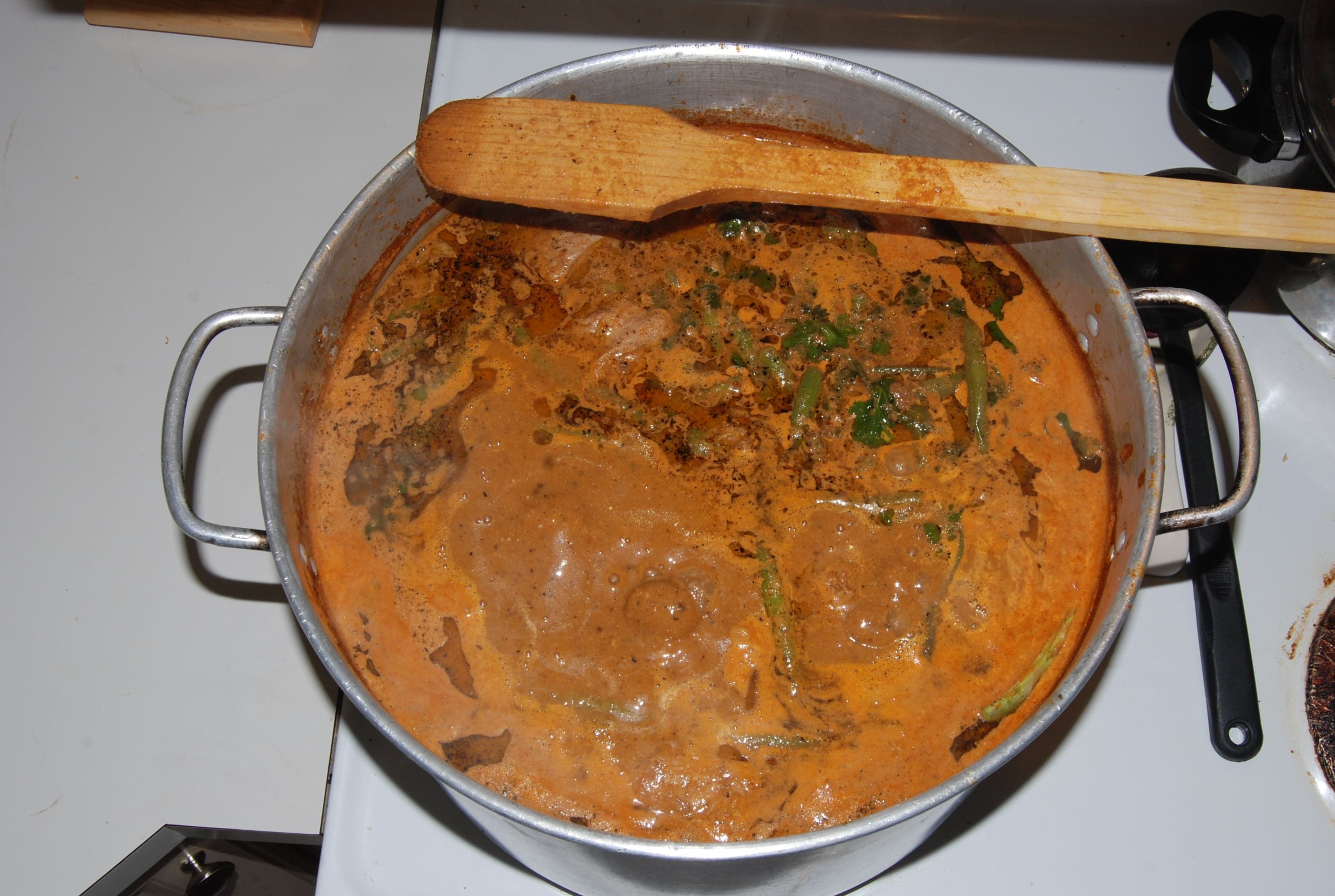 A bowl of dark red pepián stew served with chicken and rice