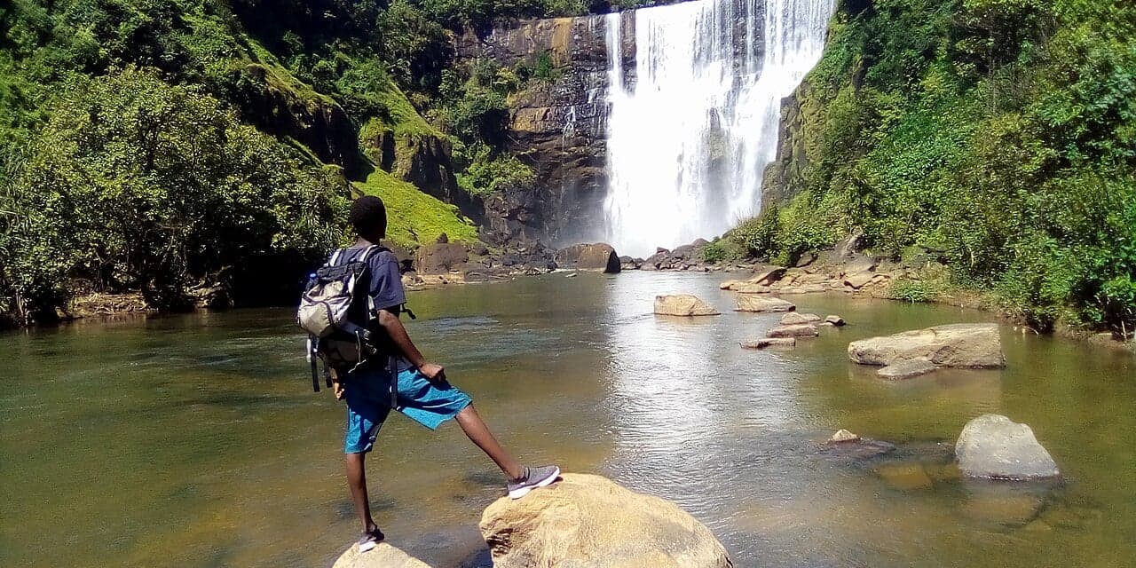 The thin, lacy cascade of Kambadaga Falls dropping through green highland vegetation