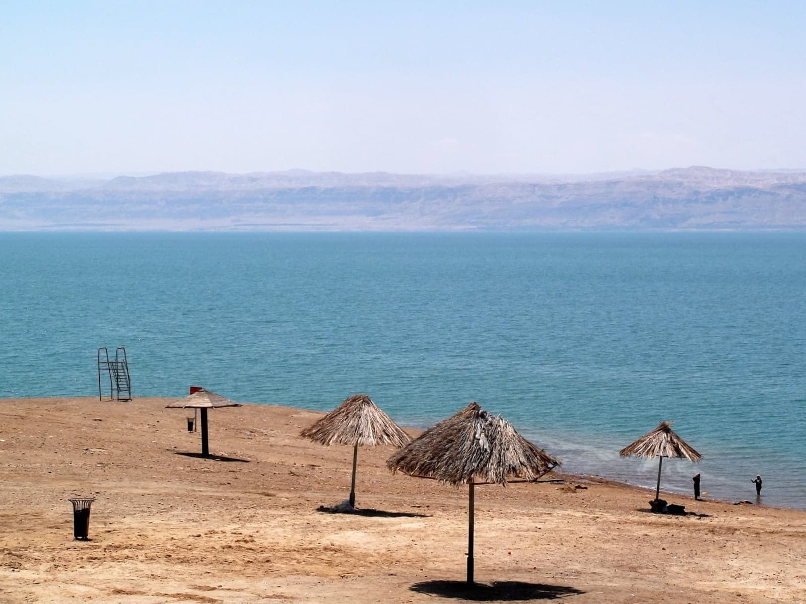Salty white shoreline of the Dead Sea with calm blue water