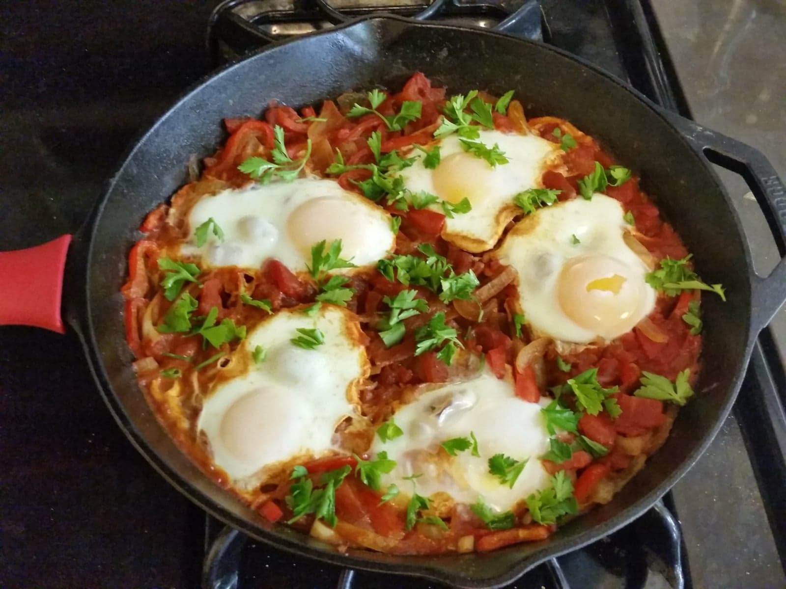A frying pan with bright red tomato sauce and poached eggs cooked into it