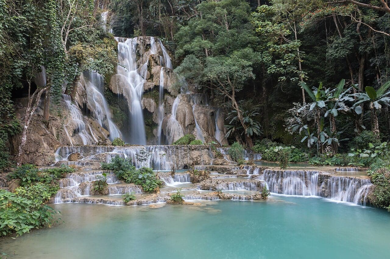 The bright turquoise pools and white cascade of Kuang Si Falls surrounded by jungle