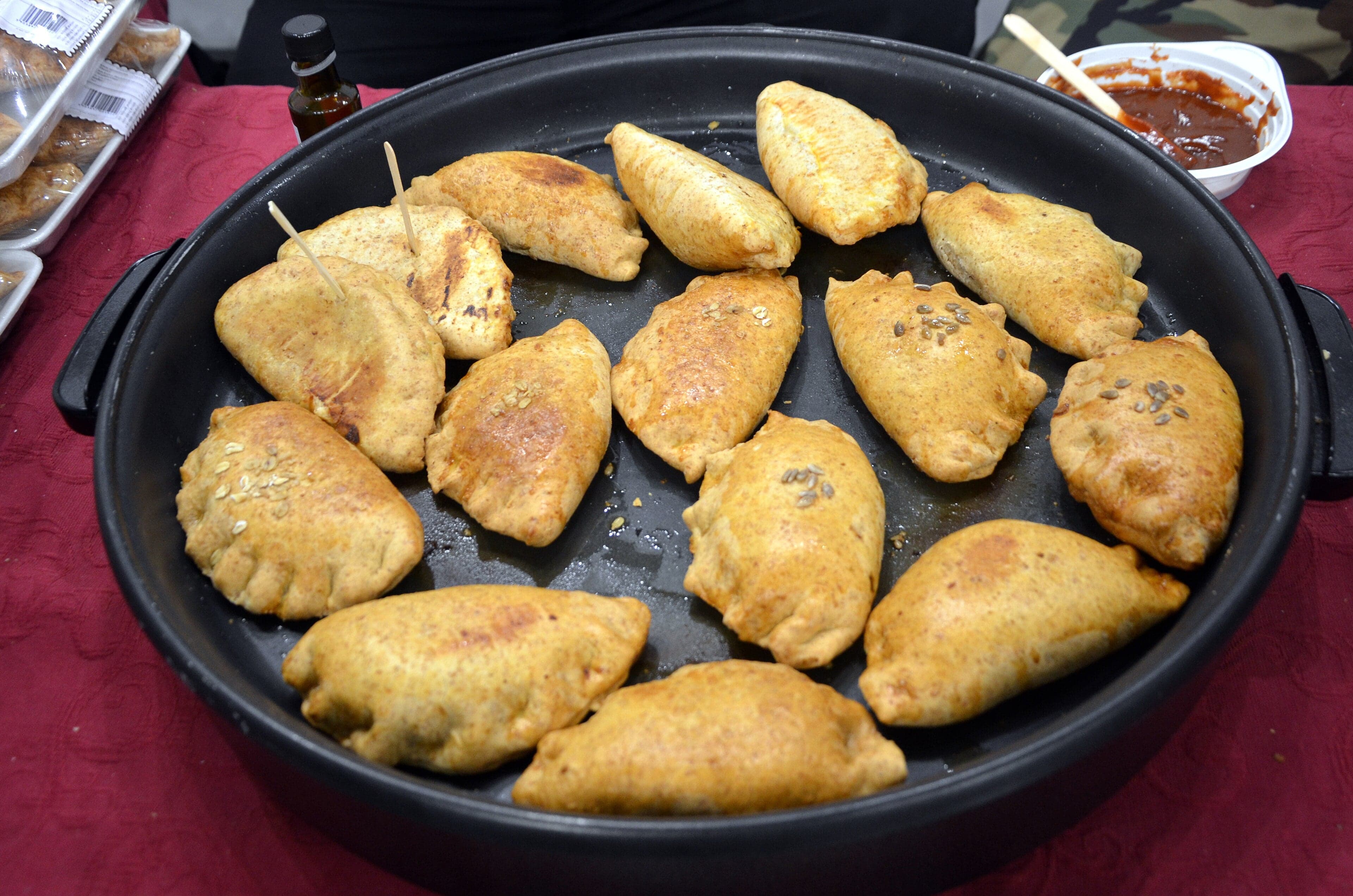 Golden crescent-shaped kibinai pastries on a wooden board with a cup of tea