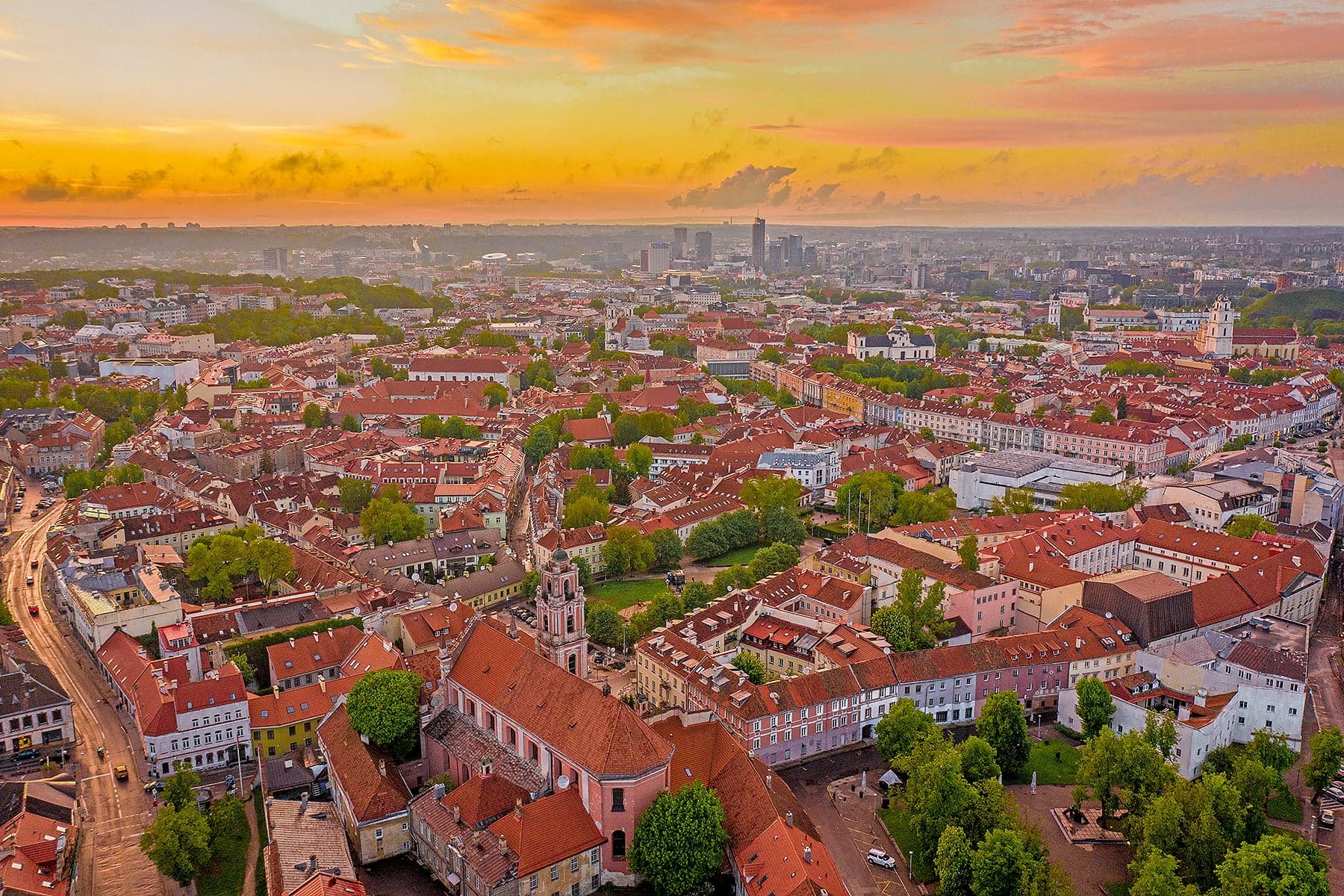 The rooftops and church spires of Vilnius Old Town spread beneath a blue sky