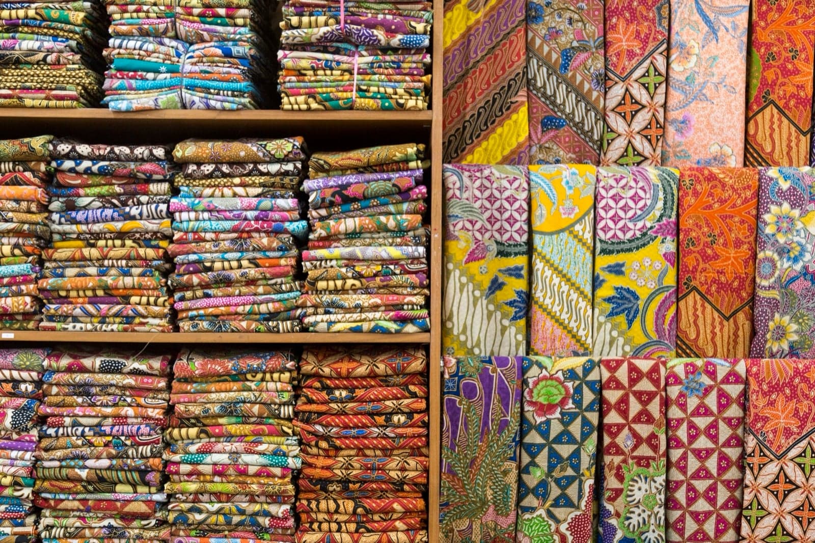 A piece of bright Malaysian batik fabric with flower and leaf patterns in red, blue and yellow