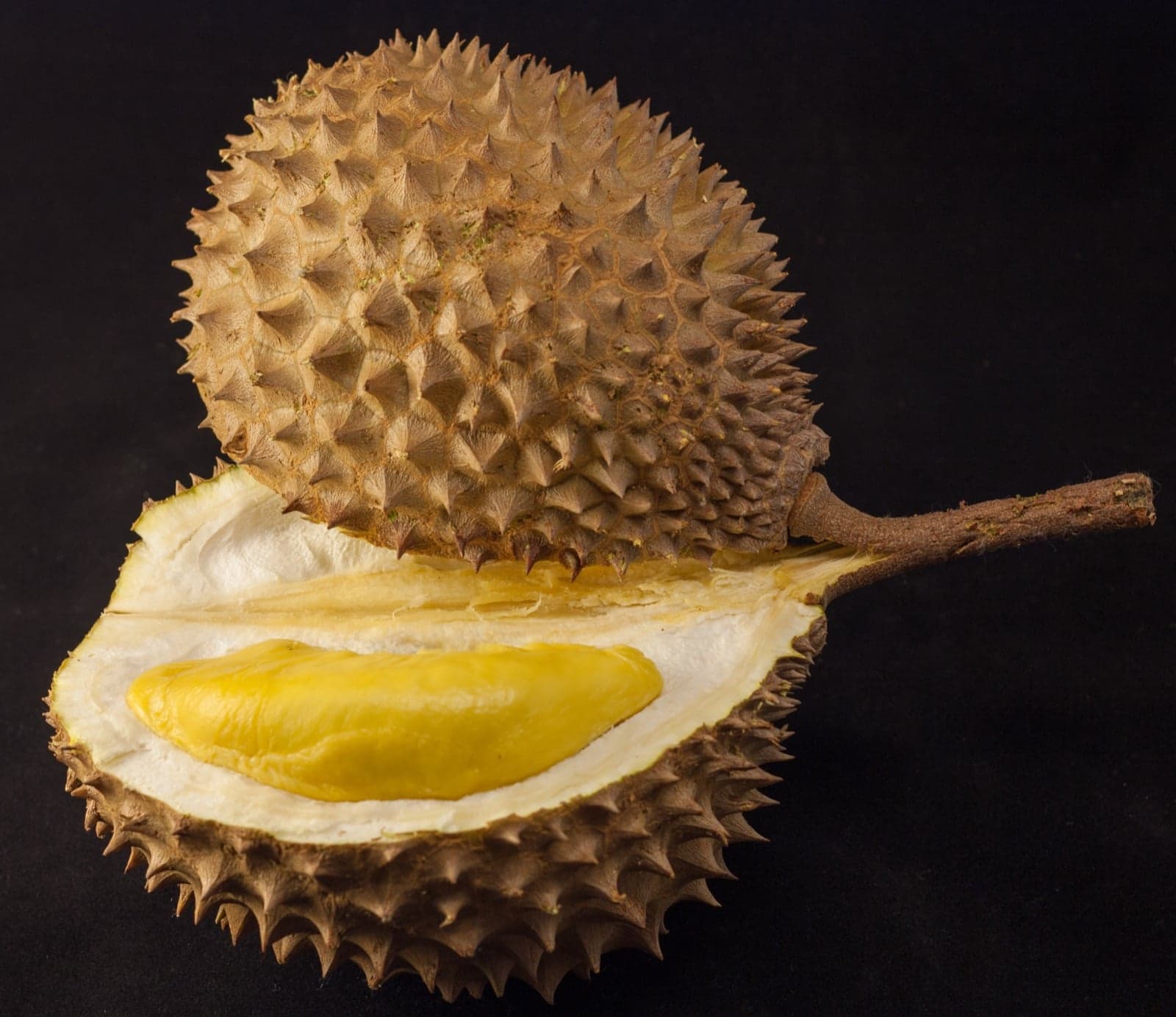 Spiky green durian fruits piled up at a Malaysian market stall