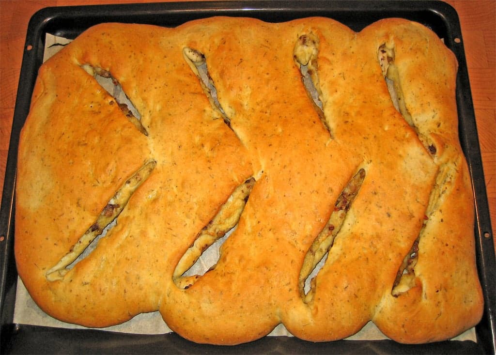 A golden fougasse bread with cut-out holes in a leaf pattern