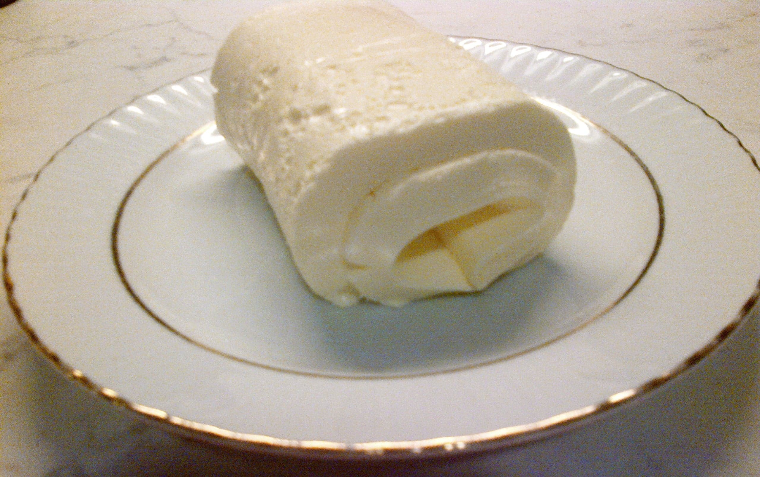 A wooden bowl filled with soft white kajmak cream cheese beside fresh bread