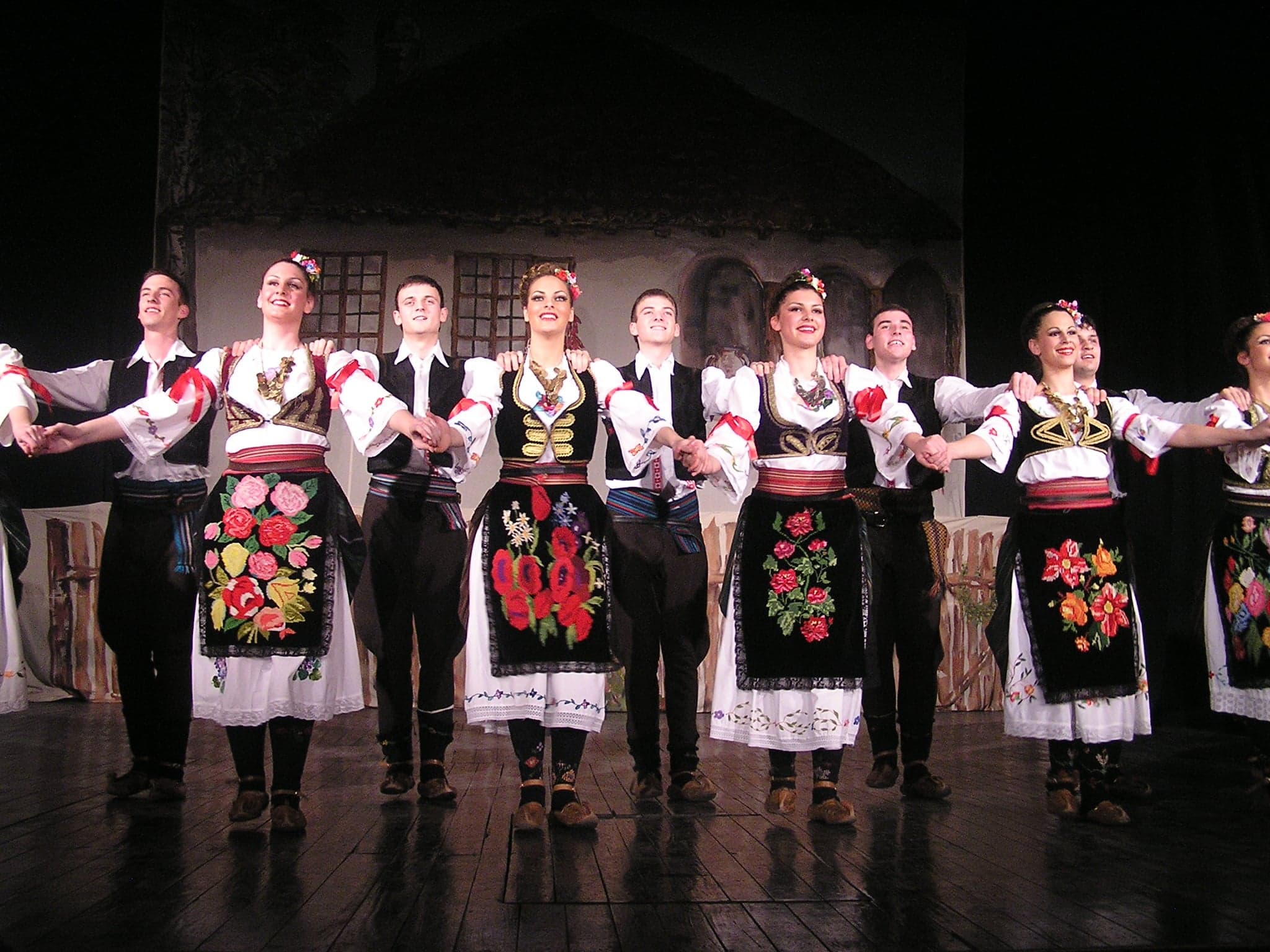 A group of dancers in colourful traditional costumes holding hands in a circle dance