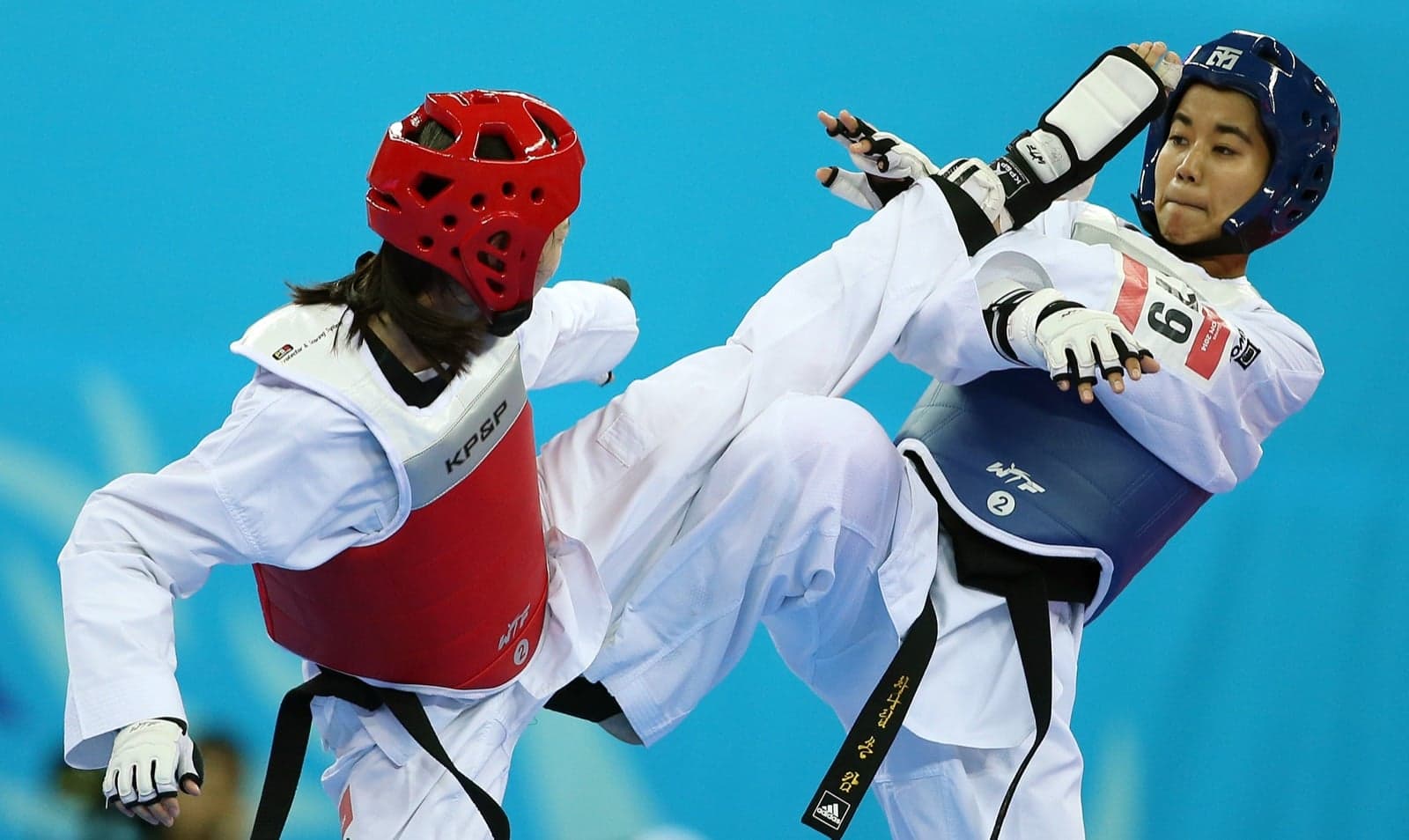 Two taekwondo athletes in helmets and chest guards facing off