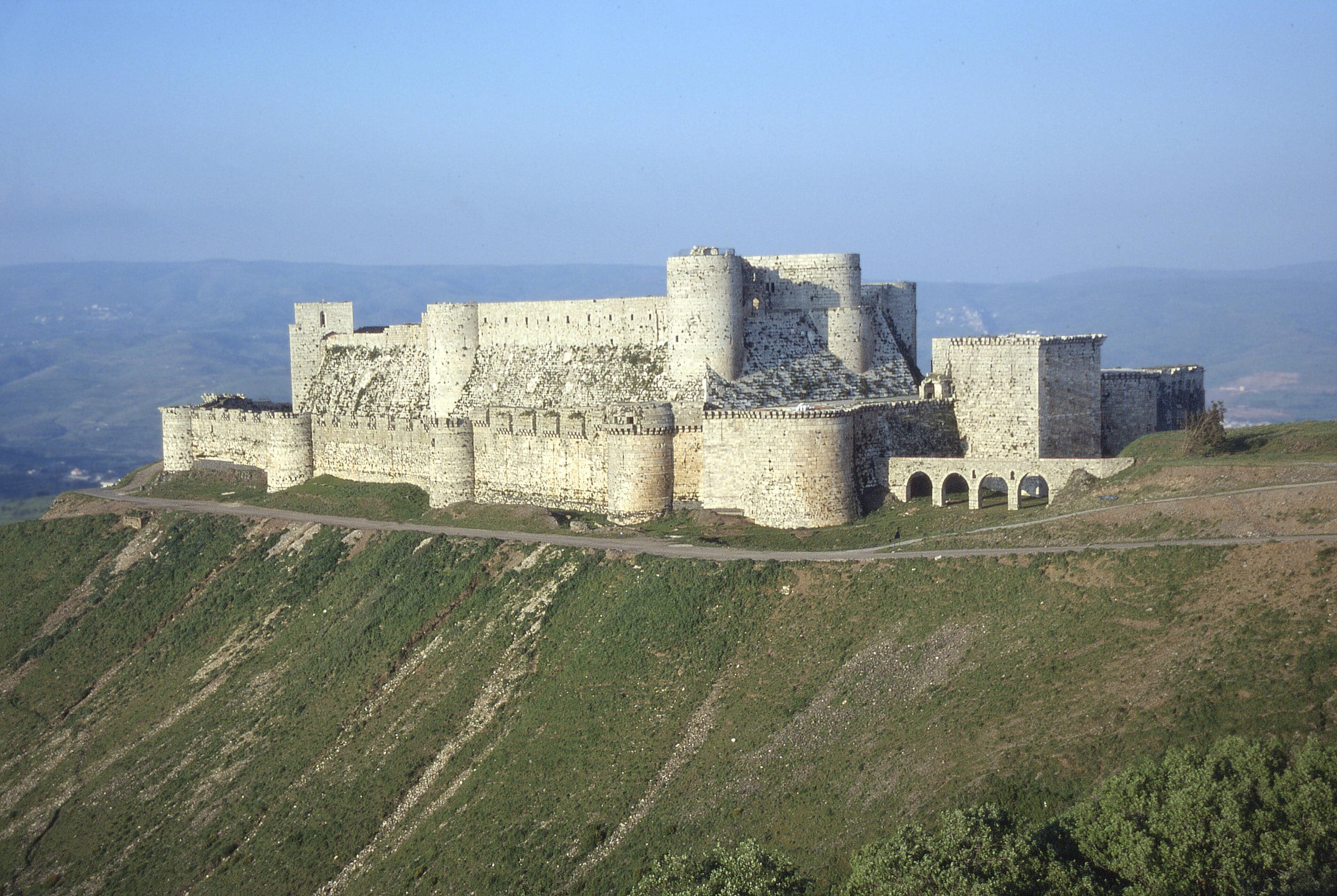 The massive stone walls and towers of Krak des Chevaliers on a hilltop