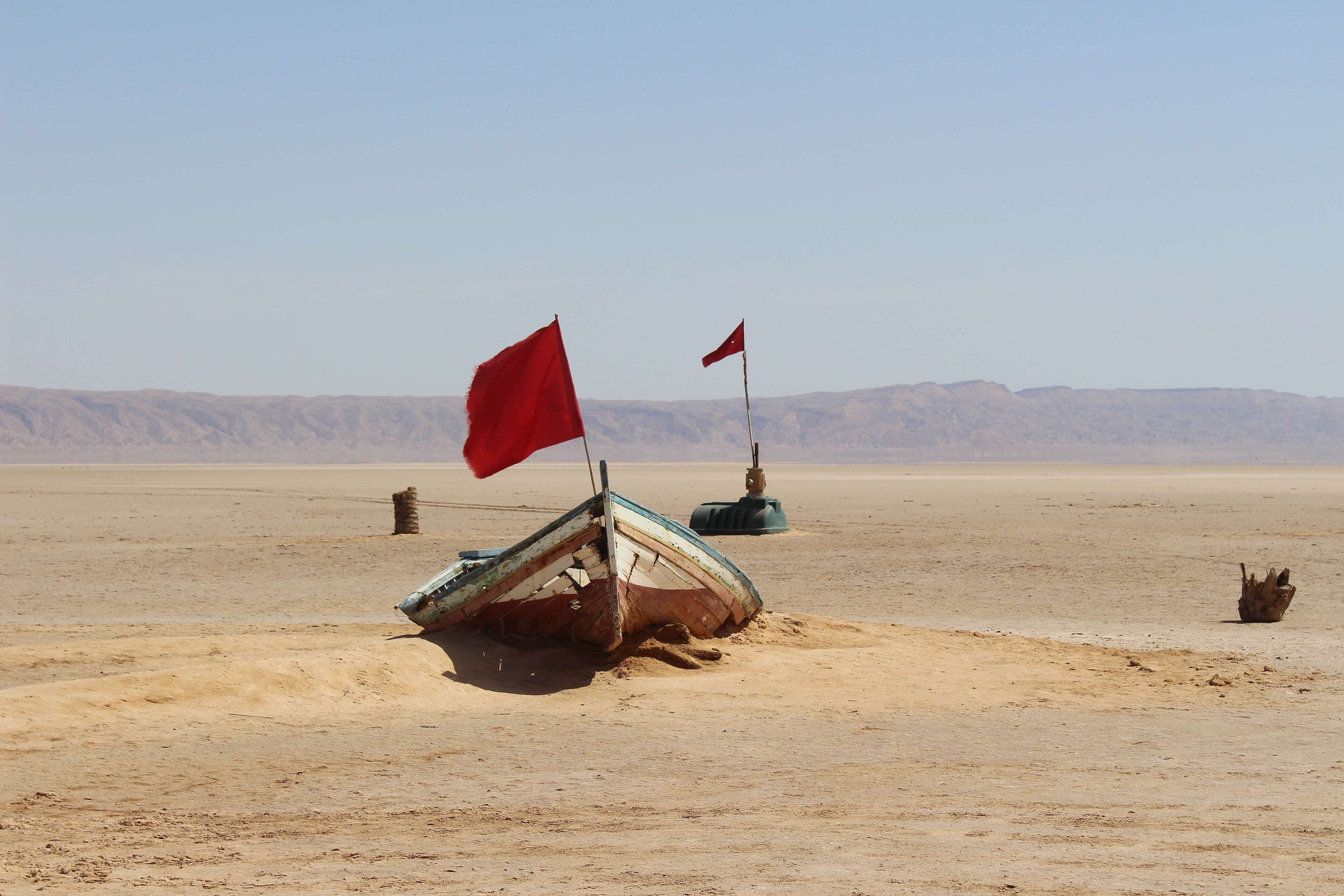 The flat shimmering surface of Chott el Djerid with a pink and orange sunset reflected in it
