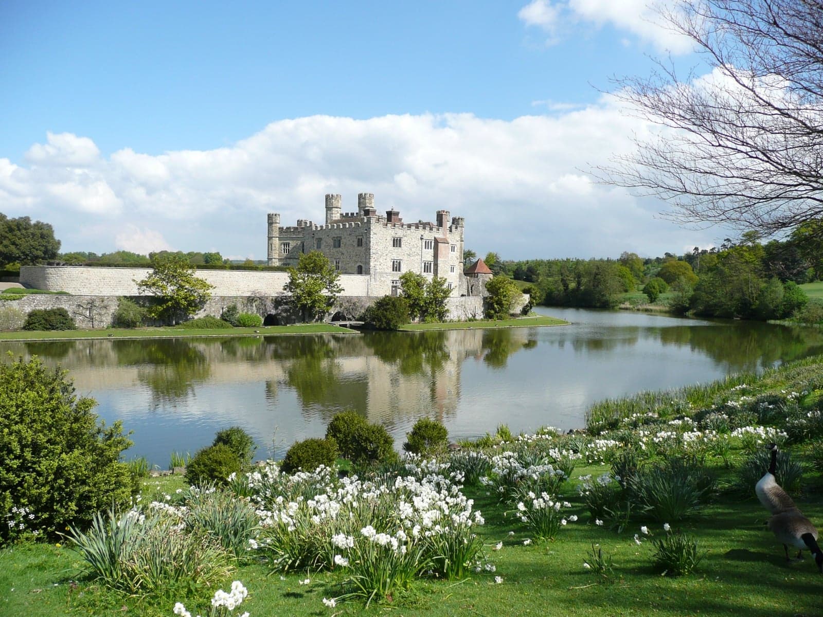 Leeds Castle in Kent, England, reflected in a calm lake on a sunny day