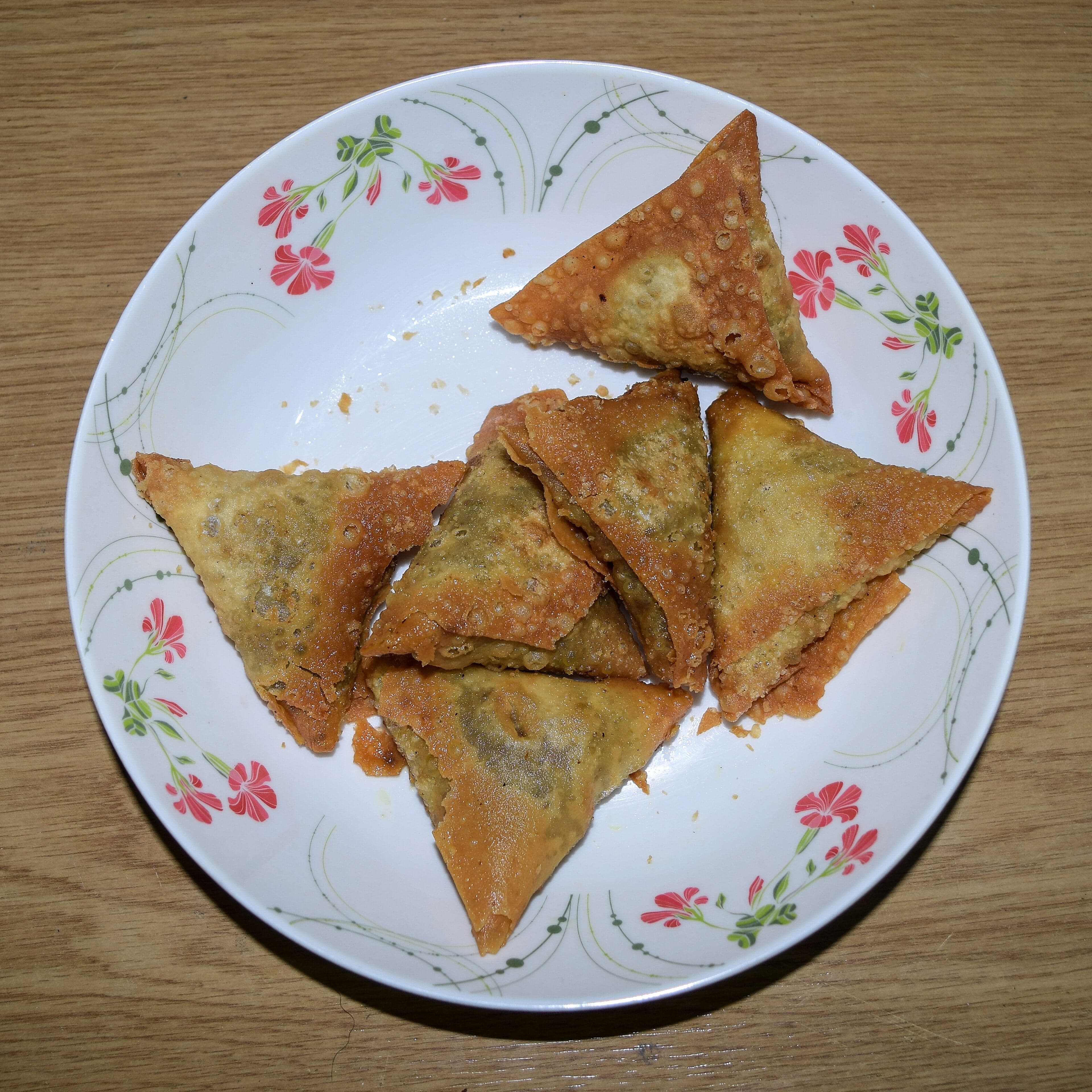 A tray of golden, triangular Uzbek samsas with sesame seeds on top