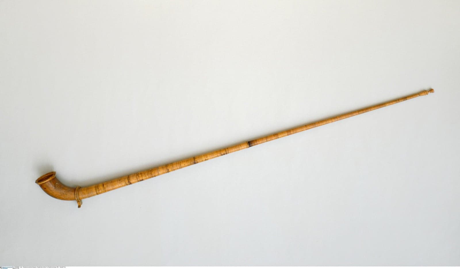 A musician playing a long wooden alphorn in the Swiss Alps